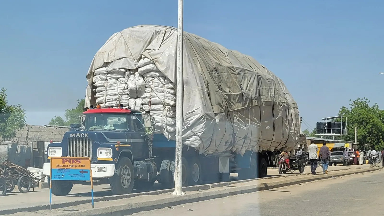 A lorry on a road, its tarpaulin load stacked far higher than the cab.